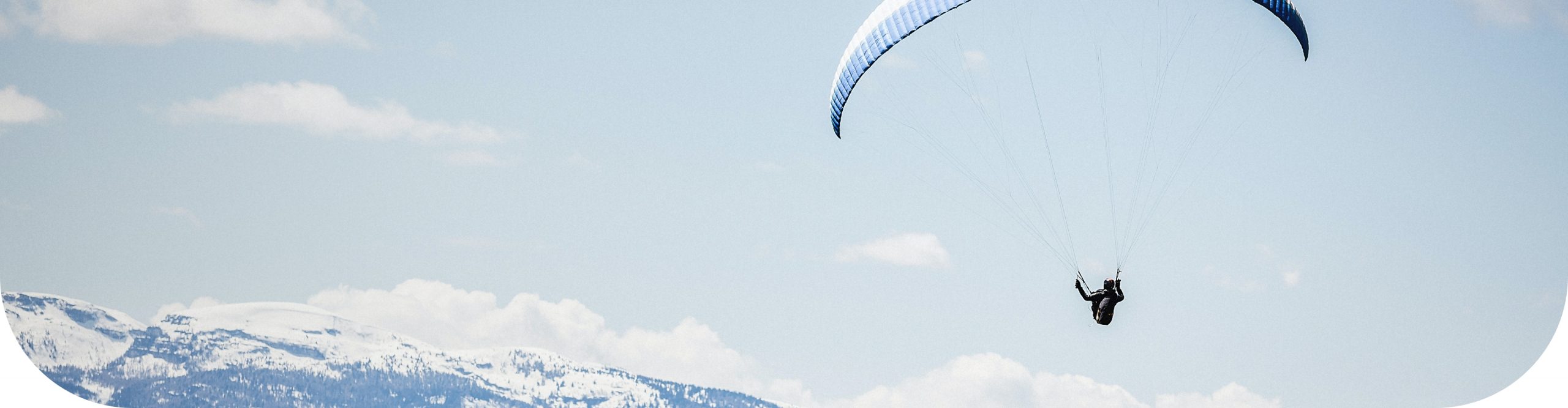 fondo de un paisaje de cielo en el que aparece una persona practicando parapente